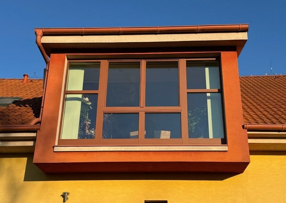 Arkýřové okno zrenovované oranžovou hliníkovou kapotážou